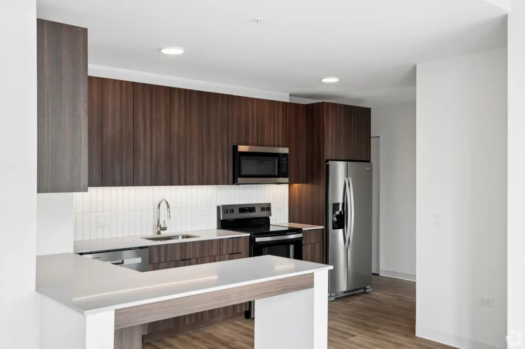 Modern kitchen with a marble waterfall island, wood cabinetry, stainless steel appliances, and pendant lights.