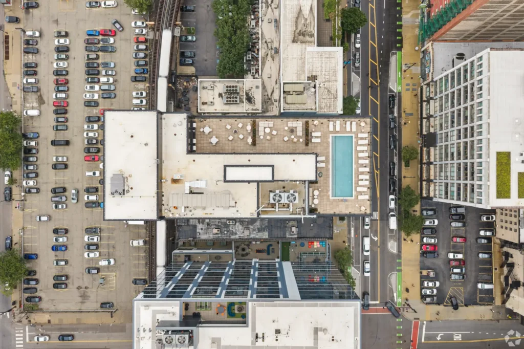 Top-down rendering of a high-rise tower with rooftop decks, surrounded by streets and neighboring buildings.
