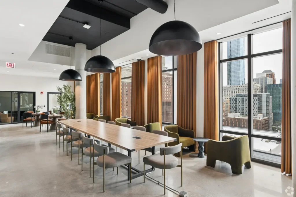 Coworking lounge with a pool table, leather seating, communal tables, and floor-to-ceiling windows.