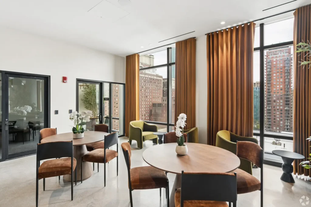 Coworking lounge with a shuffleboard table, leather chairs, green seating, and a wall-mounted TV.