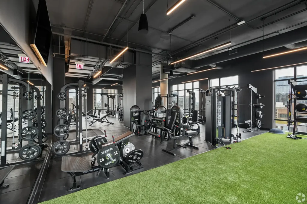 Fitness center with weight benches, dumbbell racks, strength machines, and floor-to-ceiling windows.