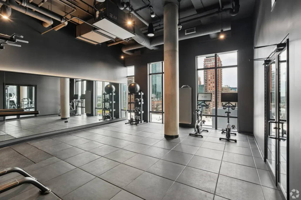 Fitness center with rowing machines, floor mats, weight equipment, and views of the pool.