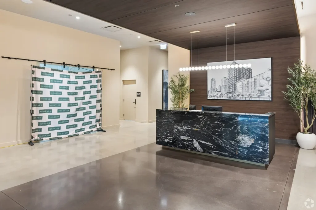 Double-height lobby with lounge seating, a fireplace, marble walls, wood paneling, and floor-to-ceiling windows.