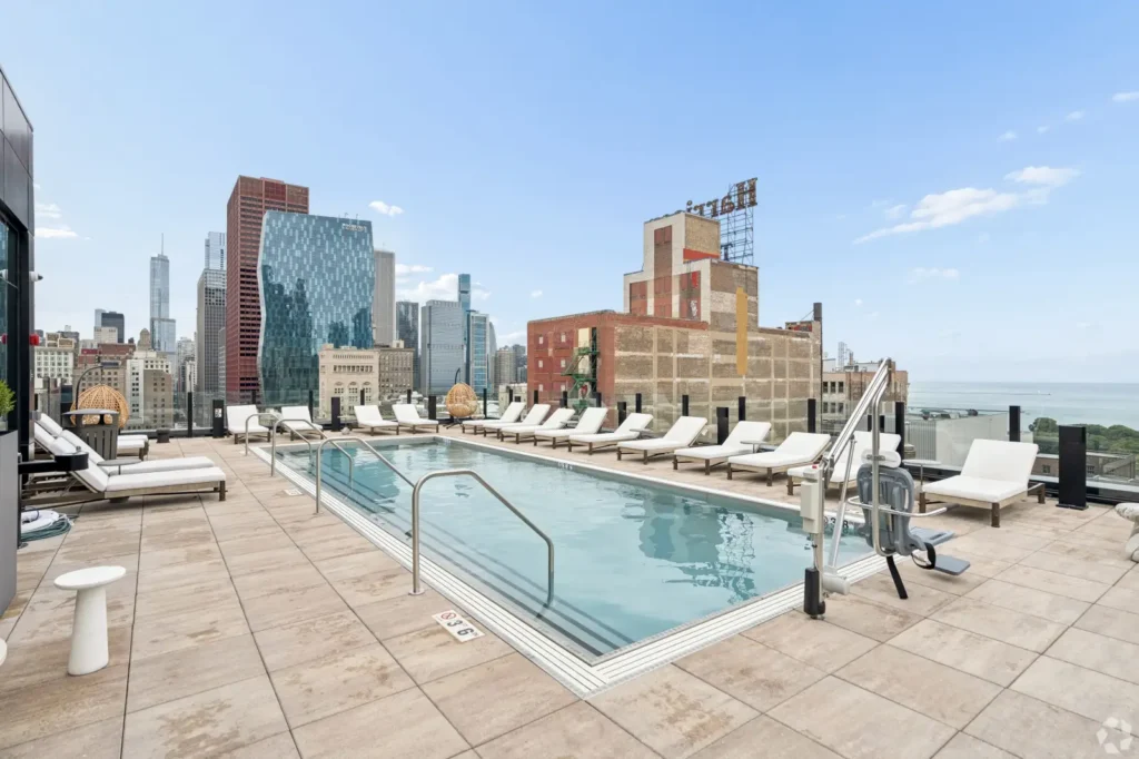 Outdoor pool with lounge chairs and floor-to-ceiling windows overlooking the Chicago skyline.