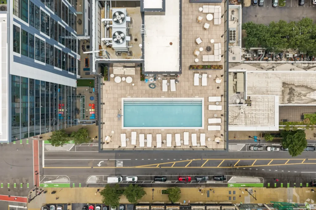 Outdoor lap pool with an accessible lift, poolside lounge seating, and skyline views through large windows.