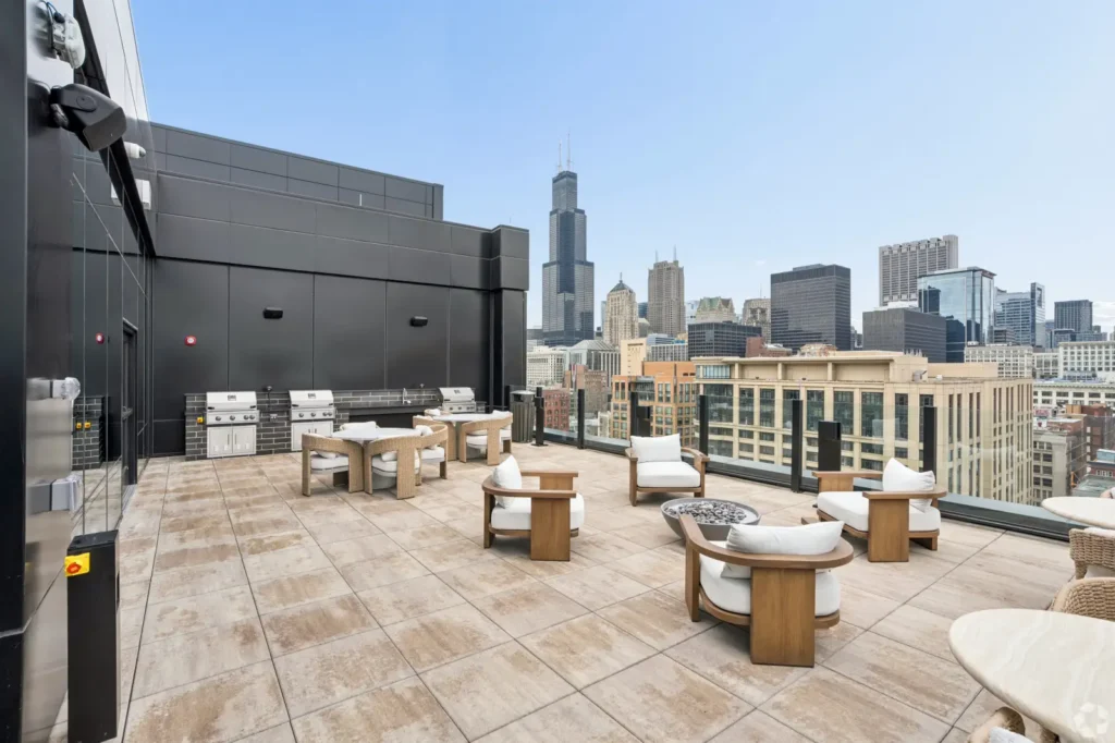 Poolside lounge with cushioned armchairs, floor lamps, and panoramic views of the Chicago skyline.