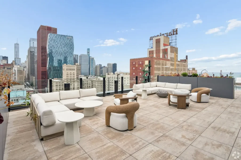 Glass-enclosed poolside lounge with sofas, armchairs, side tables, and floor-to-ceiling windows.